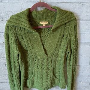 80% Wool with a V-neck and a kangaroo pouch green sweater is 20% nylon.